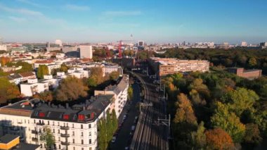 Berlin, Almanya 'da güneşli bir günde binalar ve sonbahar ağaçlarıyla çevrili bir arazinin havadan görünüşü. Dolly sol İHA 