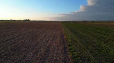 Üretilmiş tarlaları, uzak bir nehir ve ormanı olan verimli bir ovanın havadan görünüşü batan güneşin sıcacık ışığında yıkanmıştı. uçuş üstü insansız hava aracı 