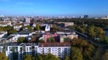 Berlin 'de bir köprüyü geçen trenin manzarası. Etrafı canlı sonbahar yapraklarıyla çevrili. İHA yükseliyor 