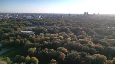 Tiergarten Park 'ın canlı sonbahar yeşillikleri üzerinde yükselen ikonik Berlin zafer sütununun havadan görünüşü. Arka planda şehir manzarası var. Sol İHA 'ya dön 