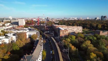 Berlin 'de bir köprüyü geçen trenin manzarası. Etrafı canlı sonbahar yapraklarıyla çevrili. Takip uçuş dronu 