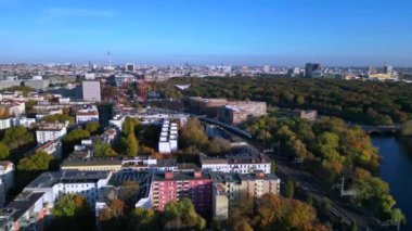 Berlin 'de bir köprüyü geçen trenin manzarası. Etrafı canlı sonbahar yapraklarıyla çevrili. panorama genel görünüm dronu 