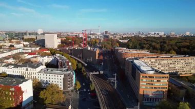 Berlin 'de bir köprüyü geçen trenin manzarası. Etrafı canlı sonbahar yapraklarıyla çevrili. Ters İHA uçuşu 