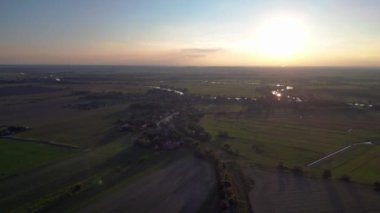 Üretilmiş tarlaları, uzak bir nehir ve ormanı olan verimli bir ovanın havadan görünüşü batan güneşin sıcacık ışığında yıkanmıştı. Yukarıdan insansız hava aracı görüntüleri 
