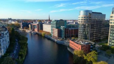 Güneşli bir günde Berlin 'in manzara manzarası... bir kanalı, bir köprüyü, binaları ve renkli sonbahar ağaçlarını içeriyor. Ters İHA uçuşu 