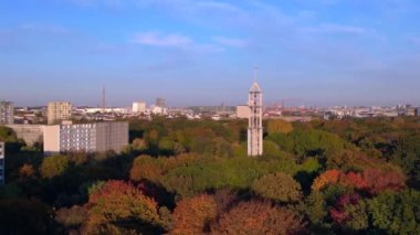 Berlins Tiergarten Parkı 'ndaki renkli sonbahar yeşilliklerinin havadan görünüşü. Şehir silueti uzakta. Ters İHA uçuşu 