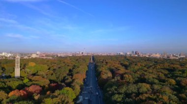 Renkli sonbahar yapraklarıyla çevrili ikonik bir dönüm noktası, açık mavi gökyüzünün altında Berlin şehri manzarası. panorama genel görünüm dronu 