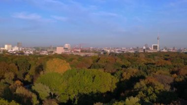 Berlins Tiergarten Parkı 'ndaki renkli sonbahar yeşilliklerinin havadan görünüşü. Şehir silueti uzakta. hız rampası hiper hareket zaman aşımı 