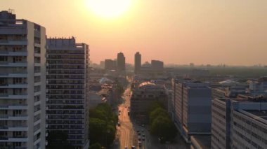 Gün batımında bir bulvarda giden arabalar, ağaçlarla ve apartmanlarla dolu bir şehir manzarasında. Yukarıdan insansız hava aracı görüntüleri 