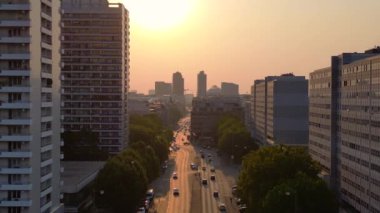 Gün batımında bir bulvarda giden arabalar, ağaçlarla ve apartmanlarla dolu bir şehir manzarasında. İHA 'yı çek 