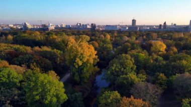Berlins Tiergarten Parkı 'ndaki renkli sonbahar yeşilliklerinin havadan görünüşü. Şehir silueti uzakta. Yukarıdan insansız hava aracı görüntüleri 