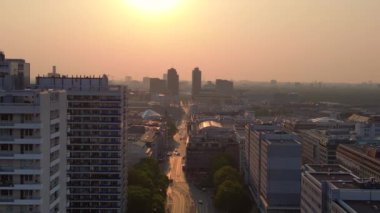 Gün batımında bir bulvarda giden arabalar, ağaçlarla ve apartmanlarla dolu bir şehir manzarasında. panorama genel görünüm dronu 