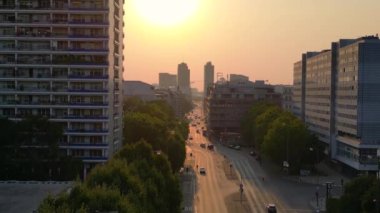 Gün batımında bir bulvarda giden arabalar, ağaçlarla ve apartmanlarla dolu bir şehir manzarasında. Ters İHA uçuşu 