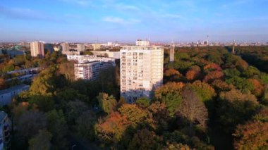 Renkli sonbahar yapraklarıyla çevrili ikonik bir dönüm noktası, açık mavi gökyüzünün altında Berlin şehri manzarası. panorama genel görünüm dronu 