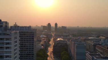 Gün batımında bir bulvarda giden arabalar, ağaçlarla ve apartmanlarla dolu bir şehir manzarasında. panorama genel görünüm dronu 