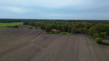Tarlalarla çevrili bir çiftlik evi, bir orman ve Almanya 'da bir yol. geniş yörünge görünümü dronu 