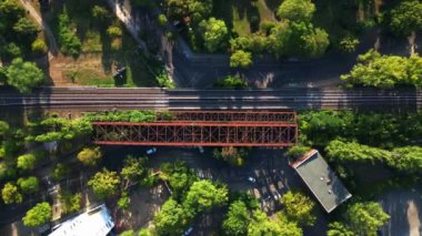 Berlin 'deki yemyeşil şehir merkezinde tren raylarının üzerinden geçen paslı demiryolu köprüsü, ulaşım altyapısı ve kentsel yeşillik entegrasyonu. hız rampası hiper hareket zaman aşımı 