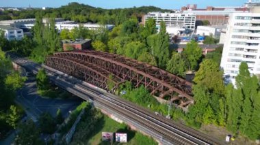 Berlin 'deki Liesenbrucke Köprüsü' nün havadan görünüşü demiryolu raylarını, duvar yazılarını, ağaçları ve çevresindeki kentsel manzarayı gösteriyor. Yukarıdan insansız hava aracı görüntüleri 
