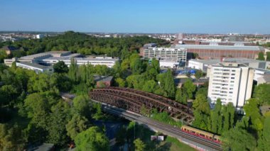 Sarı ve kırmızı tren Berlin 'deki metal köprüden geçiyor. Arka planda ikonik televizyon kulesi var, Almanya. uçuş üstü insansız hava aracı 
