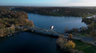 Berlin, Almanya 'da güneşli bir sonbahar gününde arabalı Glienicke Köprüsü ve Havel Nehri' ni geçen bir tur teknesi. hız rampası hiper hareket zaman aşımı 