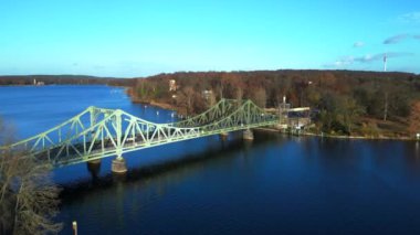 Havel nehrinin üzerindeki glienicke köprüsünün renkli bir sonbahar günbatımında üzerinde arabalar geziniyor. İticileri ileri çalıştır 
