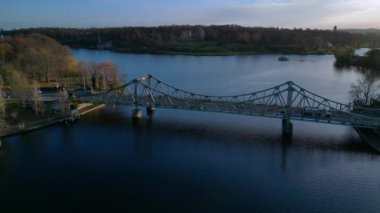 Berlin, Almanya 'da güneşli bir sonbahar gününde arabalı Glienicke Köprüsü ve Havel Nehri' ni geçen bir tur teknesi. uçuş üstü insansız hava aracı 