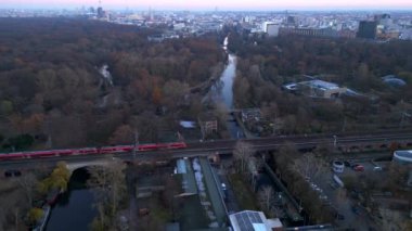 Berlin zoolojik bahçesinin, demiryollarının ve şehir manzarasının altın saat günbatımında görüntüsü. İHA alçalıyor 