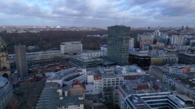 Berlin 'in hava manzarası bulutlu bir gökyüzü altında modern ve tarihi binaları, sokakları ve kentsel yoğunluğu gösteriyor. Sağ drona döndür 