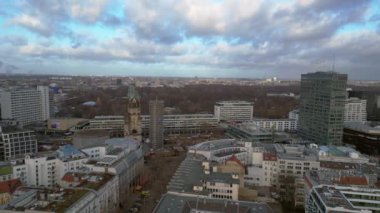 Berlin 'in hava manzarası bulutlu bir gökyüzü altında modern ve tarihi binaları, sokakları ve kentsel yoğunluğu gösteriyor. panorama genel görünüm dronu 