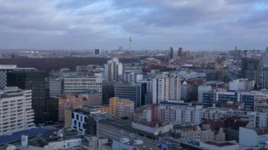 Berlin 'in hava manzarası bulutlu bir gökyüzü altında modern ve tarihi binaları, sokakları ve kentsel yoğunluğu gösteriyor. statik üç ayaklı insansız hava aracı 