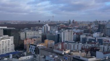 Berlin 'in hava manzarası bulutlu bir gökyüzü altında modern ve tarihi binaları, sokakları ve kentsel yoğunluğu gösteriyor. Ters İHA uçuşu 