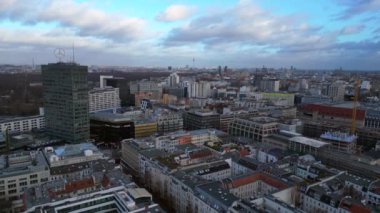 Berlin 'in hava manzarası bulutlu bir gökyüzü altında modern ve tarihi binaları, sokakları ve kentsel yoğunluğu gösteriyor. uçuş üstü insansız hava aracı 