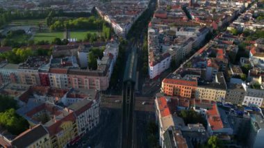 Berlin 'deki bir yerleşim bölgesinden geçen yükseltilmiş tren, şehrin taşıma sistemini gösteriyor. İHA kamerası aşağıya bakıyor 