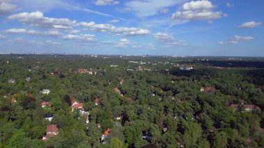 Hayır, Berlin 'de bir yerleşim bölgesi. Yoğun bir ormanın içine yerleştirilmiş evler var. Ufukta şehrin ufku görünüyor. Yukarıdan insansız hava aracı görüntüleri 