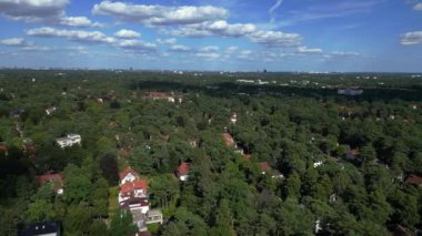 Hayır, Berlin 'de bir yerleşim bölgesi. Yoğun bir ormanın içine yerleştirilmiş evler var. Ufukta şehrin ufku görünüyor. Dolly sol İHA 