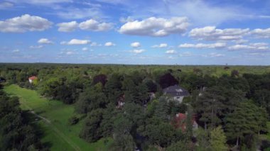 Hayır, Berlin 'de bir yerleşim bölgesi. Yoğun bir ormanın içine yerleştirilmiş evler var. Ufukta şehrin ufku görünüyor. İHA alçalıyor 