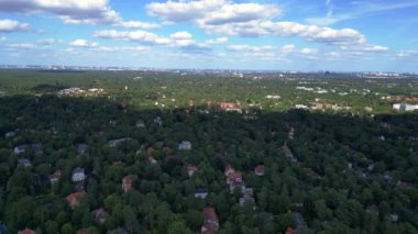 Hayır, Berlin 'de bir yerleşim bölgesi. Yoğun bir ormanın içine yerleştirilmiş evler var. Ufukta şehrin ufku görünüyor. Dolly sol İHA 