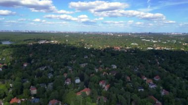 Hayır, Berlin 'de bir yerleşim bölgesi. Yoğun bir ormanın içine yerleştirilmiş evler var. Ufukta şehrin ufku görünüyor. Yukarıdan insansız hava aracı görüntüleri 