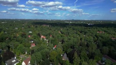 Hayır, Berlin 'de bir yerleşim bölgesi. Yoğun bir ormanın içine yerleştirilmiş evler var. Ufukta şehrin ufku görünüyor. uçuş üstü insansız hava aracı 