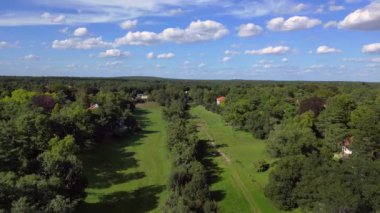 Schlachtensee gölleri, güneşli bir günde, masmavi gökyüzü ve bulutlarla çevrili yemyeşil ormanlarla çevrilidir. İticileri ileri çalıştır 
