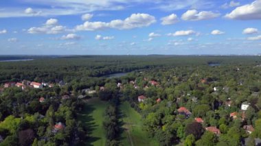 Schlachtensee gölleri, güneşli bir günde, masmavi gökyüzü ve bulutlarla çevrili yemyeşil ormanlarla çevrilidir. panorama genel görünüm dronu 