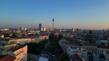 Berlin TV kulesi çatıların üstünde yükseliyor ve gün batımında Senefelderplatz 'da bir inşaat sahası var. Yukarıdan insansız hava aracı görüntüleri 