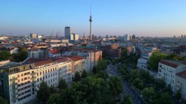 Berlin TV kulesi çatıların üstünde yükseliyor ve gün batımında Senefelderplatz 'da bir inşaat sahası var. doly sağ drone 