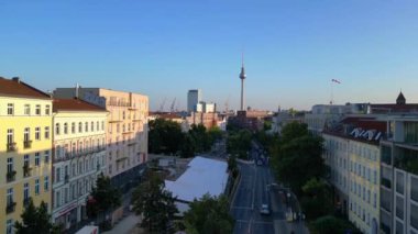 Berlin TV kulesi çatıların üstünde yükseliyor ve gün batımında Senefelderplatz 'da bir inşaat sahası var. İHA yükseliyor 