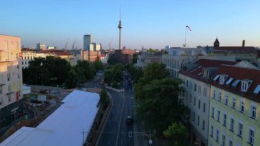 Berlin TV kulesi çatılardan yükseliyor ve gün batımında Senefelderplatz 'da bir inşaat sahası var. uçuş üstü insansız hava aracı 