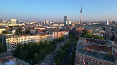 Berlin TV kulesi çatıların üstünde yükseliyor ve gün batımında Senefelderplatz 'da bir inşaat sahası var. panorama genel görünüm dronu 
