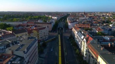 Berlin 'in yerleşim bölgesinden geçen sarı yükseltilmiş tren. Ters İHA uçuşu 