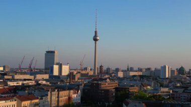 Berlin TV kulesi şehrin üzerinde dikiliyor, altın saatin sıcacık parıltısıyla yıkanıyor. İHA alçalıyor 