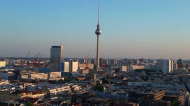 Berlin TV kulesi şehrin üzerinde dikiliyor, altın saatin sıcacık parıltısıyla yıkanıyor. doly sağ drone 