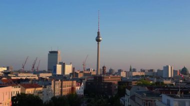 Berlin TV kulesi şehrin üzerinde dikiliyor, altın saatin sıcacık parıltısıyla yıkanıyor. İHA yükseliyor 